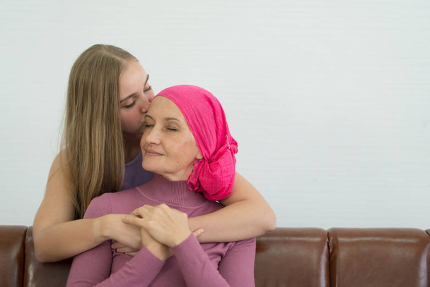 Jonge volwassen vrouwelijke kankerpatiënt die tijd doorbrengt met haar dochter thuis. Neem geneeskunde familie ondersteuning concept. - Foto, afbeelding