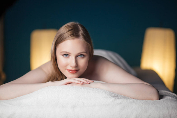 Young, beautiful woman in spa salon lying on the coach waiting for massage. - 写真・画像