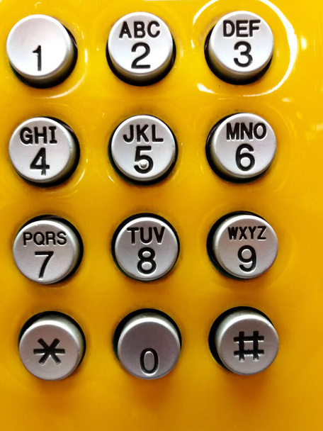 Teclado de numeración de teléfono gris o gris para pulsar para llamar sobre fondo amarillo. - Foto, Imagen