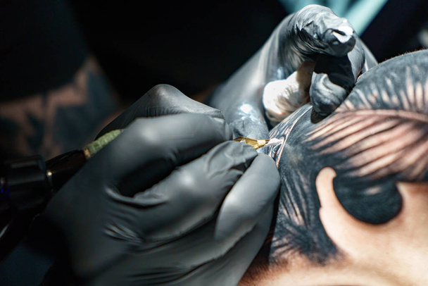 Immagine di maestro che fa il tatuaggio nero di serpente per donna - Foto, immagini