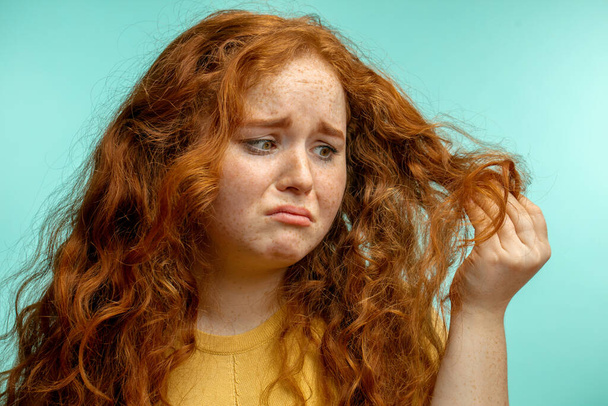 Upset and woman with her damaged dry hair face expression blue background - Foto, imagen