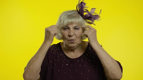愚かなジェスチャーを示す不満が高齢者の女性を悩ませます.黄色の背景のおばあちゃん - 映像、動画