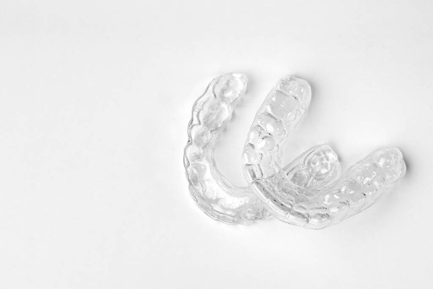 Ortodoncia invisible tirantes extraíbles sobre un fondo blanco con espacio de copia. Alineadores para enderezar los dientes - Foto, imagen