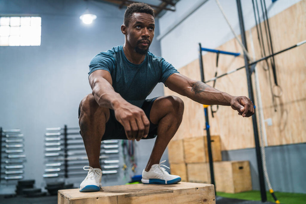 Portrait of an athletic man doing box jump exercise. Crossfit, sport and healthy lifestyle concept. - Photo, image
