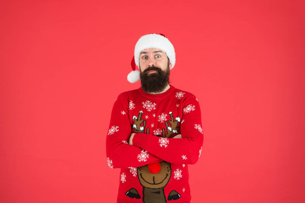 ready for xmas party. happy new year. cheerful hipster funny knitted sweater. warm clothes in cold winter weather. holiday season mood. bearded man santa hat red background. merry christmas - Photo, Image