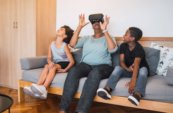 Portrait of African American grandmother and grandchildren playing together with VR glasses at home. Family and technology concept. - Fotoğraf, Görsel