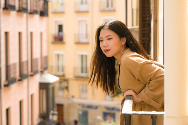 young happy and beautiful Asian Chinese woman enjoying city view from hotel room balcony in Spain during holidays trip in Europe smiling cheerful in urban background - Fotó, kép