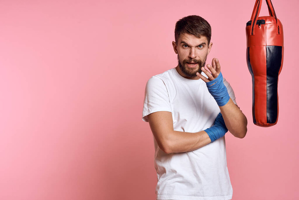 Człowiek ćwiczenia ciosy na gruszki boks bandaże fitness styl życia różowy tło - Zdjęcie, obraz