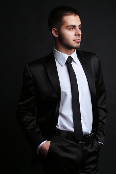 Handsome young man in suit on dark background - Foto, afbeelding