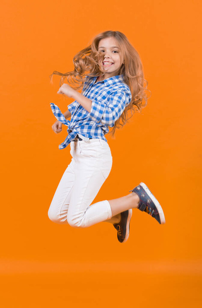 Child jump smiling on orange background - Fotoğraf, Görsel