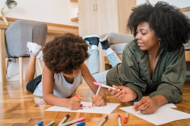Portrait of young african american mother and son drawing with colored pencils on warm floor at home. Family concept. - Foto, Bild