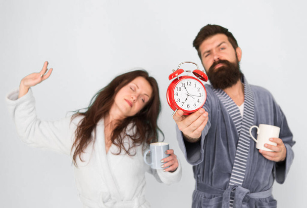 Man with beard and sleepy woman enjoy morning coffee or tea. Guy in bath clothes hold tea coffee. Breakfast concept. Every morning begins with coffee. Couple in bathrobes with mugs. Its coffee time - Foto, imagen