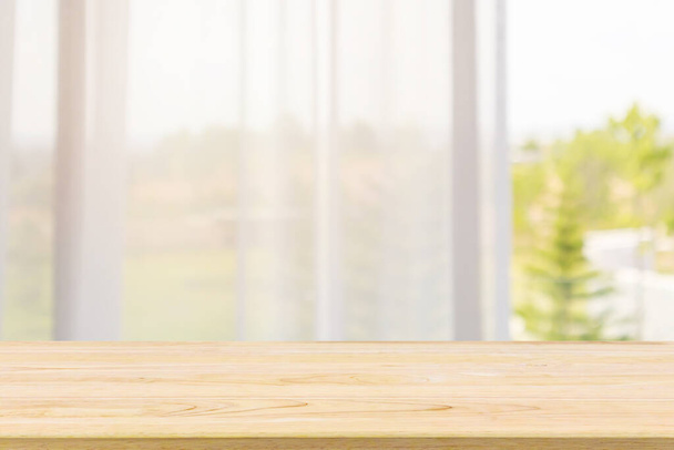 Κενό ξύλινο τραπέζι κορυφή με παράθυρο κουρτίνα αφηρημένη θαμπάδα φόντο για την οθόνη του προϊόντος - Φωτογραφία, εικόνα