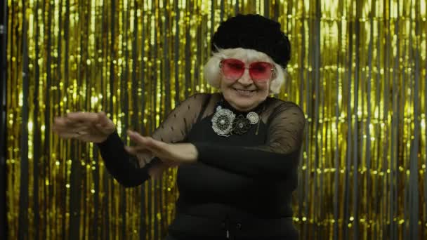 Idős öregasszony táncol, ünnepel, zenét hallgat. Energetikusan halad a ritmus, pihentető - Felvétel, videó