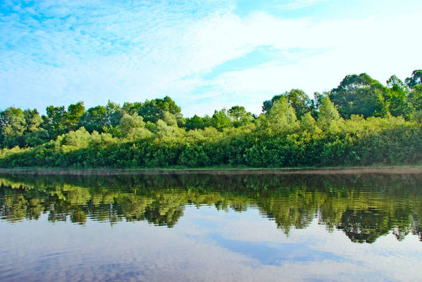 Maisema kesäjoella. Puut ja pensaat heijastuvat jokiveteen. Kesämetsä. Metsäjoen vedenpinta. Kaunis kesämaisema. Matkustuskäsite - Valokuva, kuva