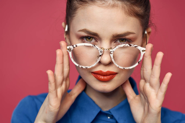 Portré egy nő szemüvegben és egy kék ing piros ajkak rózsaszín háttér modell - Fotó, kép