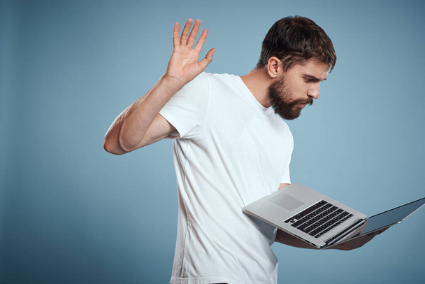 Homem emocional com laptop em mãos no fundo azul monitor teclado internet modelo recortado vista - Foto, Imagem