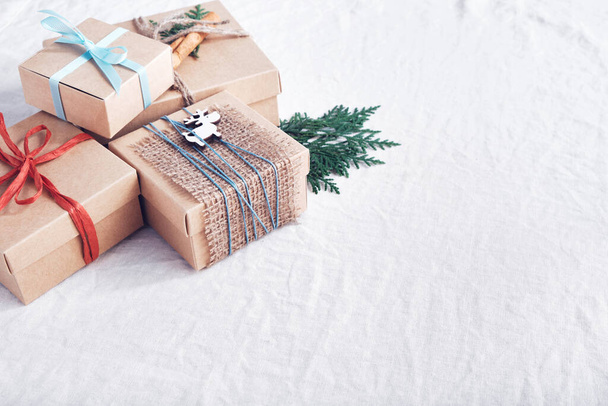 Рождественские подарки на белой смятой ткани. Экологическая упаковка. Праздники без отходов. - Фото, изображение