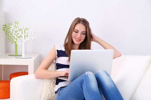 Young woman resting with laptop on sofa at home - Foto, afbeelding