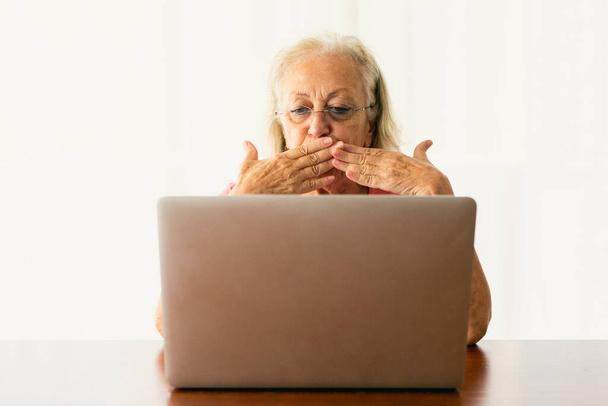 Starsza kobieta korzystająca z laptopa i prowadząca rozmowę online - Zdjęcie, obraz
