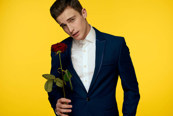 Gentleman in classic suit on yellow background with red rose romance  - Fotó, kép