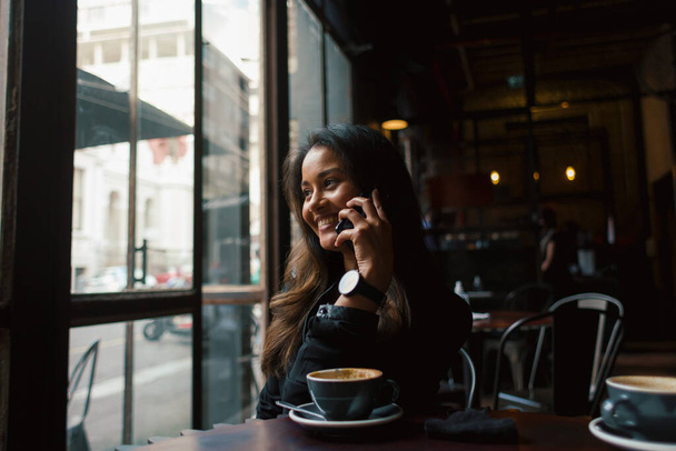 Junge Mischlingshündin mit Smartphone und Kaffee am Tisch  - Foto, Bild