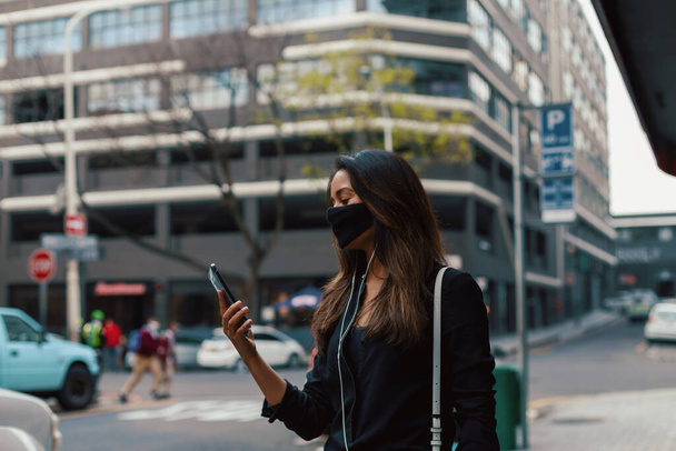 Giovane donna con smartphone indossando maschera sulla strada della città   - Foto, immagini