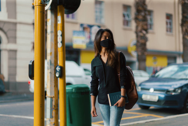 街の路上で顔のマスクを身に着けている若い女性 - 写真・画像