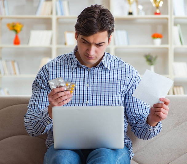 Молодой человек сидит на диване с таблетками и рецептом - Фото, изображение