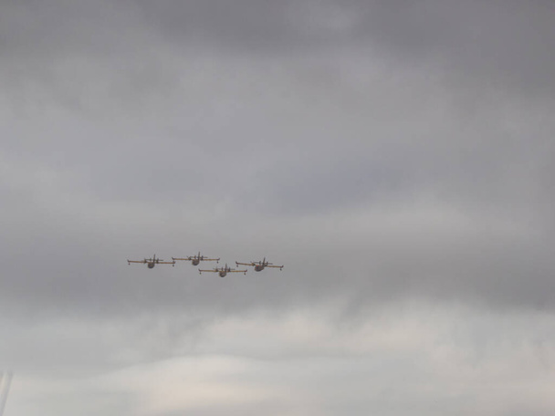 ヒスパニックの日の間にスペイン空軍のパレードの飛行機のグループが曇った空を横断 - 写真・画像