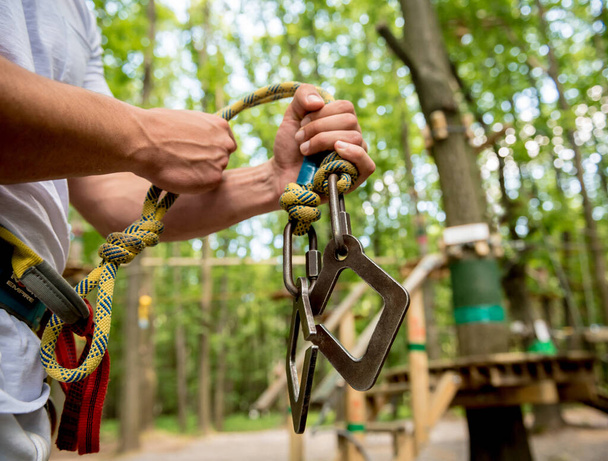 Young man in adventure rope park. Climbing Equipment. - 写真・画像