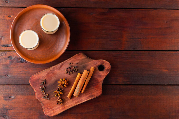 Tea with milk and spices. Indian masala chai tea on wooden boards. Autumn drink in turkish tea cups. Top view - Foto, Imagem