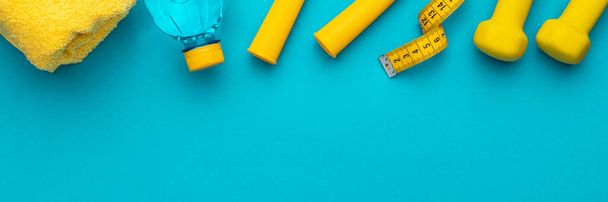 Flat lay photo of yellow fitness equipment in oder over turquoise blue backgound - Fotoğraf, Görsel