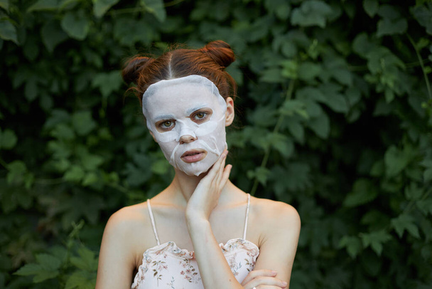 Schöne Frau weiße Maske Kosmetologie grüne Büsche im Hintergrund Kopierraum - Foto, Bild