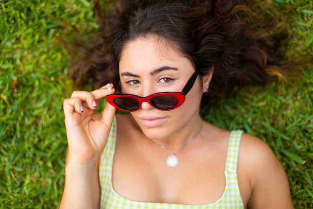 молодая девушка в солнечных очках на фоне травы вид сверху - Фото, изображение