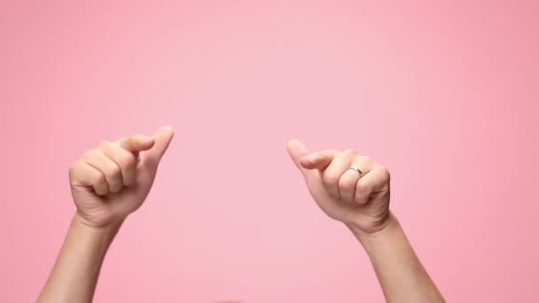 ręce człowieka wskazując palce w powietrzu, co kciuki w górę znak i taniec na różowym tle - Materiał filmowy, wideo