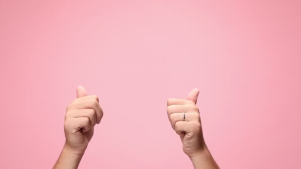 мужчина держит руки над головой, делает большой палец вверх жест, присоединение и нажатие руки на розовый фон - Кадры, видео