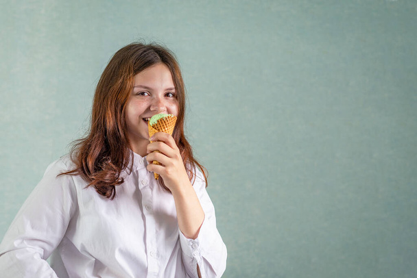 A young girl bites a pistachio ice cream in a waffle cup - Fotoğraf, Görsel