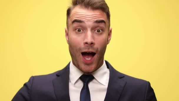 close-up van een jonge zakenman het maken van een geschokt gezicht bewegen op een gelukkig verrast een, schudden zijn handen, glimlachen, schreeuwen hardop en wijzen naar voren op gele achtergrond - Video