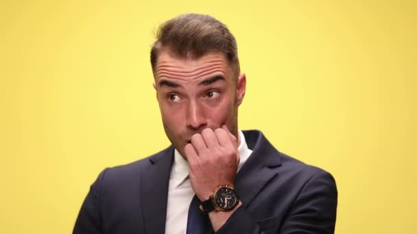 close up of a scared businessman, touching his mouth with his hand, looking around and making worries on yellow background - Footage, Video