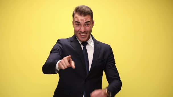 attraente uomo d'affari che punta alla fotocamera con una mano poi con entrambe le mani, facendo un segno ok con le mani in aria su sfondo giallo - Filmati, video