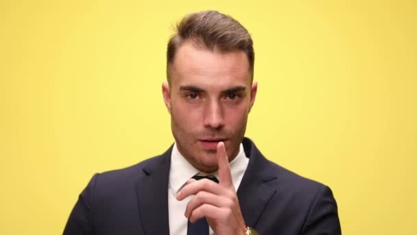 primer plano de un joven empresario pidiendo silencio sobre fondo amarillo - Metraje, vídeo