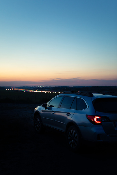 夜間の車のテールライト。街の明かりを背景に。コピースペース - 写真・画像