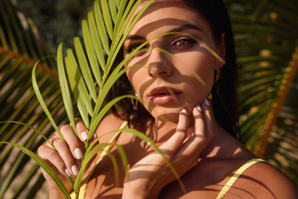 mooie charme vrouw groene palm bladeren exotische tropen luxe van de zon jungle levensstijl - Foto, afbeelding