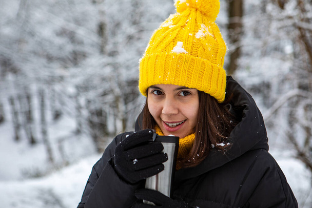 glimlachende vrouw in de winter outfit drinken warm up drankje uit navulbare mok kopieerruimte - Foto, afbeelding