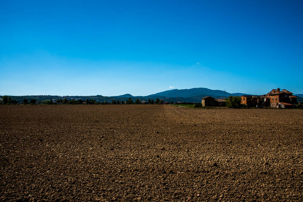 beautiful image of a brown plowed field with a blue sky in the background on the way to Citerna, Perugia, Umbria, Italy - Фото, зображення