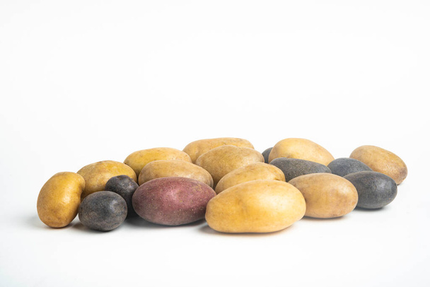 Різний колір сирої і свіжої картоплі майстерно розташований і встановлений на плоскій білій поверхні столу фону
. - Фото, зображення