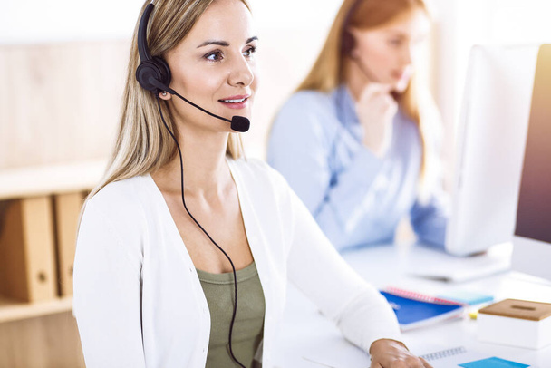 Toned portrait of call center operator at work. Group of people in a headset ready to help customers. Business concept - Фото, зображення