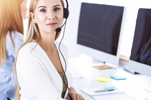 Toned portrait of call center operator at work. Group of people in a headset ready to help customers. Business concept - Foto, imagen