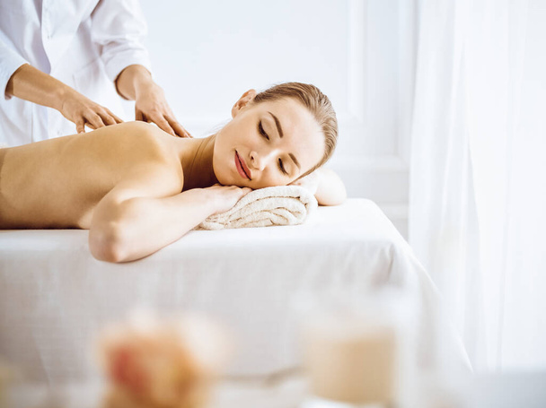 Beautiful woman enjoying back massage with closed eyes. Spa treatment concept. - Photo, image